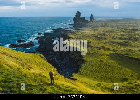 Mann Wanderer in gelber Jacke stehen auf dem Gipfel des Felsens im Outdoor-Park in Island. Londrangar Stockfoto