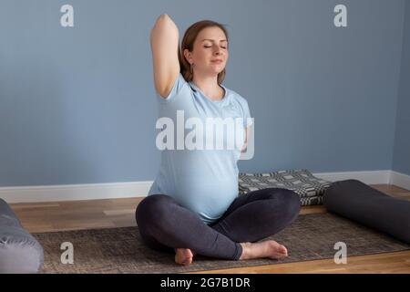 Schwangerin, die pränatalen Yoga in Yoga-Pose macht und dabei Hände und Brust streckt. Stockfoto