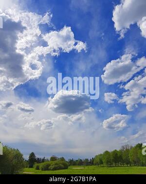 Blauer Himmel mit Wolken über grüner Landschaft Stockfoto