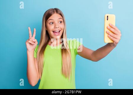 Foto von jungen ziemlich schön charmant positiv lächelndes Mädchen, das Selfie auf dem Telefon zeigen V-Zeichen isoliert auf blauem Hintergrund Stockfoto