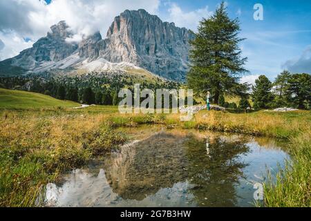 Frau beim Wandern in Gröden. Teich und Spiegelung des Langkofelgebirges. Dolomiten, Italien Stockfoto