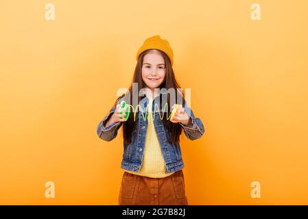 Ein Mädchen in einem mehrfarbigen Hemd hält ein mehrfarbiges, slinky Spielzeug In ihren Händen Stockfoto