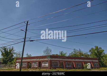 Augusta, GA USA - 04 22 21: Altes altes verlassene Backsteingebäude mit vernagelten Fenstern und klarem blauen Himmel Stockfoto