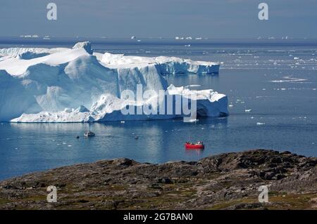 Rotes Boot vor großen Eisbergen, Sermeq Kujalleq, Disko Bay, Grönland, Dänemark Stockfoto