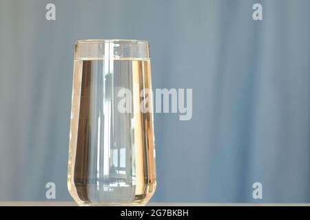 Glasbecher mit sauberem Trinkwasser isoliert auf blauem Hintergrund. Stockfoto