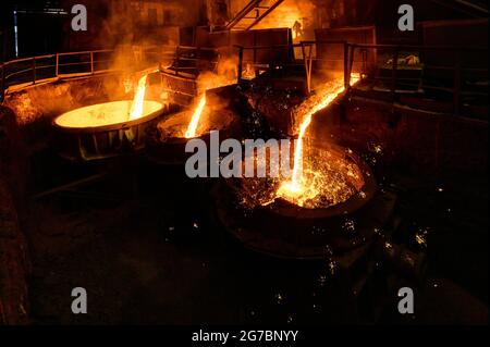 Ein Strahl aus geschmolzenem Stahl wird in Schöpfkellen gegossen. Metallurgische Industrie Stockfoto