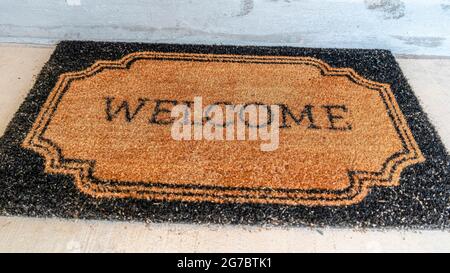 Pano Home Eingang mit Welcome Fußmatte vor der Haustür und grauer Haustür Stockfoto