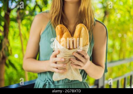 Wiederverwendbare Lebensmittellaschen mit Brot in den Händen einer jungen Frau. Keine Abfallbeseitigung. Null-Abfall-Konzept Stockfoto