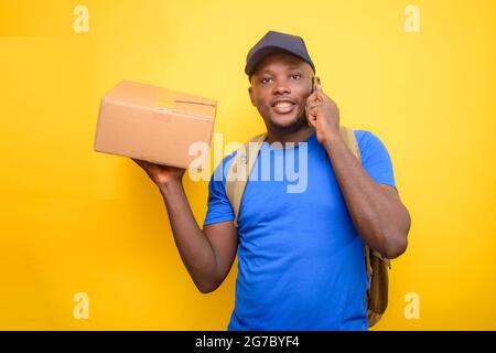 Ein afrikanischer Entsendungsmann mit Rucksack, der einen Anruf abgab, Boxen trug und eine Gesichtskappe trug Stockfoto