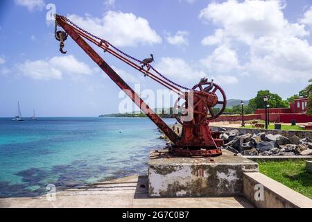 Ein Pelikan sonnt sich in der Sonne, während er auf einem alten Hafenkran am Pier in Frederiksted, St. Croix, USVI, thront. Stockfoto