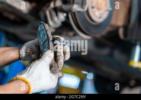 Kfz-Mechaniker oder Serviceman Überprüfung einer Scheibenbremse und Asbest-Bremsbeläge ist es ein Teil des Pkw-Nutzung für Stopp das Auto für die Sicherheit in der Auto-Reparatur-Service-Cen Stockfoto