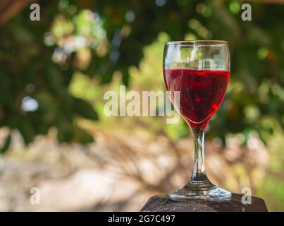 Ein Glas Rotwein wird auf einen Holztisch gestellt. Am Morgen Meeresatmosphäre des Sommers Stockfoto