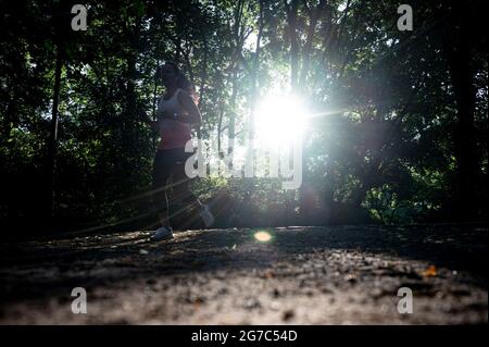 Berlin, Deutschland. Juli 2021. Bei Sonnenaufgang läuft ein Jogger durch den Volkspark Friedrichshain. Quelle: Fabian Sommer/dpa/Alamy Live News Stockfoto