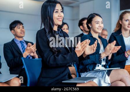 Professionelles junges asiatisches und kaukasisches Publikum applaudiert in der Gruppenmeeting-Präsentation von der Partnerschaft im Büro. Geschäftsleute und Stockfoto