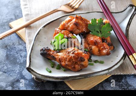 Gegrillte Hähnchendrumsticks im asiatischen Stil, serviert auf einem Gericht, das zum Mittagessen fertig ist Stockfoto