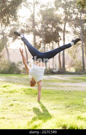 Vorderansicht eines gymnastischen Mann Handstandes auf einer Hand, der akrobatische Haltung macht Stockfoto