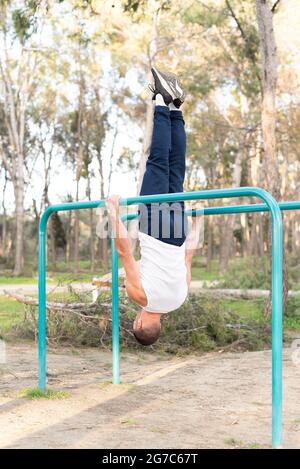 Männlicher Athlet, der auf parallelen Stäben Kopf bis zum Boden trainiert Stockfoto