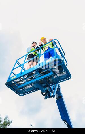 Bauarbeiter vor Ort in hydraulischen Hebebühne über das Projekt auf Pad oder Tablet-computer Stockfoto