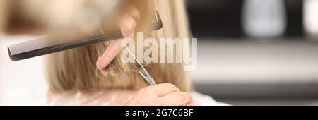 Friseur hält Kamm und Schere in den Händen und schneidet Haare des Kunden Stockfoto