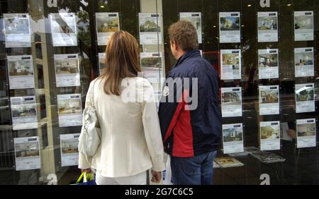 Aktenfoto vom 02/09/08 eines Paares, das vor dem Fenster eines Immobilienmaklers stand. Laut einer Umfrage bedauert die Hälfte der Menschen, die während der Coronavirus-Pandemie ein Haus gekauft haben, wie viel sie bezahlt haben. Rund 94 % der Menschen, die seit März 2020 ein Haus gekauft haben, gaben an, dass sie sich unter Druck gesetzt hatten, schnell zu kaufen, was normalerweise nur 46 Minuten dauerte, um ihre Immobilie zu sehen, fand Aviva heraus. Ausgabedatum: Dienstag, 13. Juli 2021. Stockfoto