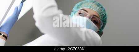 Medic hält eine Röntgenaufnahme in einer medizinischen Schutzmaske Stockfoto