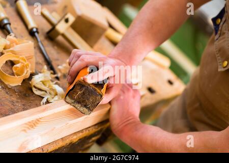 Tischler arbeiten mit einem Schleifblock und Schleifpapier in seiner Werkstatt Stockfoto