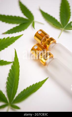 Hanfblätter und Ölflaschen auf weißem Hintergrund Stockfoto