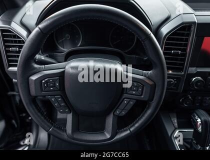 Lenkrad des Fahrzeugs. Innenraum des Fahrzeugs. Innenansicht des Autos mit schwarzem Salon. Stockfoto