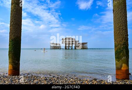 Brighton UK 13. Juli 2021 - ein Paddelboarder am frühen Morgen genießt die Sonne am West Pier von Brighton, da in den nächsten Tagen das heiße Wetter in Großbritannien eintreffen wird, wobei die Temperaturen bis zum Wochenende die hohen 20 Grad erreichen werden: Credit Simon Dack / Alamy Live News Stockfoto