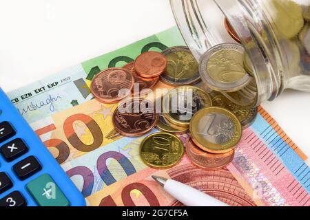 Eine Nahaufnahme der finanziellen Stillleben von Euro-Banknoten, Münzen und einem Stift. Stockfoto