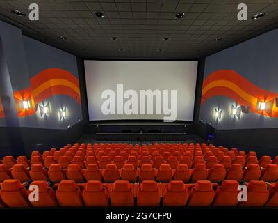 Im Inneren des großen Kinos. Leere Sitze warten auf den Film auf dem weißen Bildschirm. Ihr Text oder Bild auf dem weißen Bildschirm. Stockfoto
