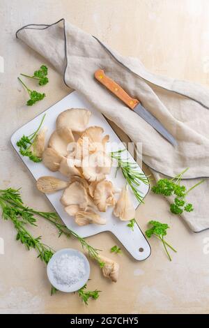 Bio Austernpilze mit Kräutern und Salz auf Schneidebrett Stockfoto