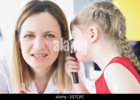 Kleines Mädchen untersucht Ohr mit Otoskop an Frau Arzt Stockfoto