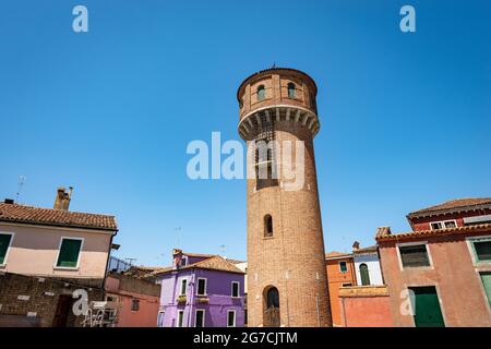 Alter Wasserturm des Aquädukts auf der Insel Burano und kleine mehrfarbige Häuser an einem sonnigen Frühlingstag. Lagune von Venedig, Venetien, Italien, Südeuropa. Stockfoto