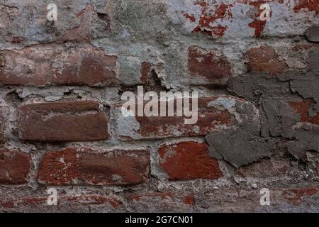 Rote Ziegelwand mit altem grauen Putz. Retro Gebäude Hintergrund Kopieplatz. Dunkelorangefarbene Oberfläche, detailreicher Steinhintergrund. Desktop-Hintergrundbild t Stockfoto