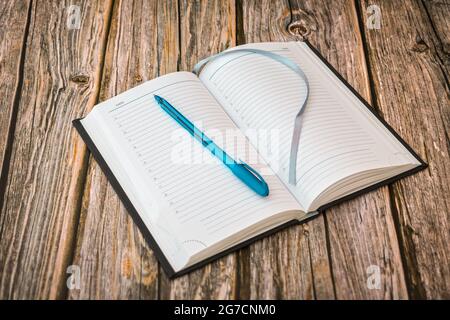 Ein offenes Tagebuch mit leeren Seiten, auf denen ein Kugelschreiber ruht und bereit ist, Ereignisse oder Aufgaben aufzuzeichnen Stockfoto