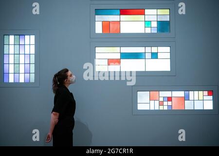 Eine Person betrachtet die geometrische Vertikal-Horizontale Komposition (Buntglasfenster für die Wohnung von Andre Horn, Straßburg) 1928 während eines Fotoaufrufs für die neue Sophie Taeuber-Arp-Ausstellung in der Tate Modern in London. Bilddatum: Dienstag, 13. Juli 2021. Stockfoto