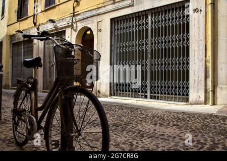 Fahren Sie mit dem Fahrrad in einer schattigen Straße mit geschlossenen Geschäften Stockfoto