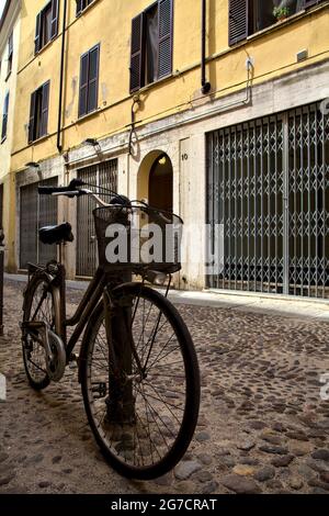 Fahren Sie mit dem Fahrrad in einer schattigen Straße mit geschlossenen Geschäften Stockfoto