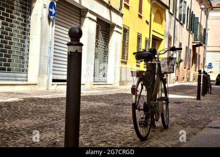 Fahren Sie mit dem Fahrrad in einer schattigen Straße mit geschlossenen Geschäften Stockfoto