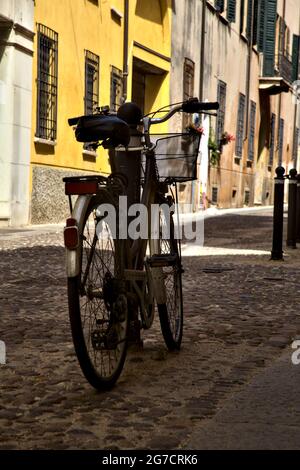 Fahren Sie mit dem Fahrrad in einer schattigen Straße mit geschlossenen Geschäften Stockfoto