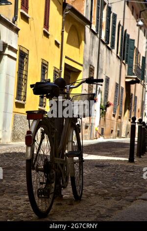 Fahren Sie mit dem Fahrrad in einer schattigen Straße mit geschlossenen Geschäften Stockfoto