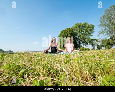 Mutter und Tochter praktizieren Yoga am Fluss - gesunde Lebensweise Stockfoto