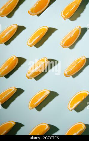 Isolierte orangefarbene Scheiben auf hellblauem Hintergrund mit kontrastierenden Schatten Stockfoto