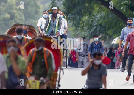 Am Dienstag, den 12. Juli, laufen oder reiten Menschen auf dem Weg zur Arbeit im Morgenrausch in Dhaka. Bangladesch durchlebt einen Anstieg von COVID-19, mit einem Rekordhoch von 13768 Fällen am Montag, dem 12. Juli. Am 14. Juli werden die Sperrbeschränkungen für neun Tage für die Eid-ul-Azha-Feierlichkeiten aufgehoben. Stockfoto