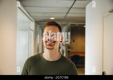 Porträt einer glücklichen männlichen Führungskraft im Büro. Fröhlicher Geschäftsmann im Coworking Space. Stockfoto