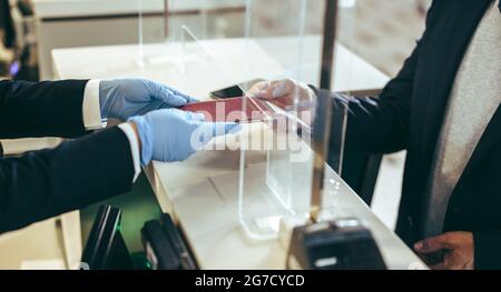 Schließung des Check-in-Schalters der Fluggesellschaft am Flughafen. Der Reisende gibt seinen Reisepass dem Flughafenpersonal für den Check-in für den Flug während der Pandemie. Stockfoto