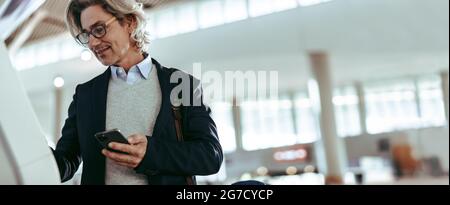 Geschäftsmann am Flughafen, der sich selbst eincheckt. Mann auf Geschäftsreisen, der den Check-in am internationalen Flughafen selbst in Anspruch genommen hat. Stockfoto