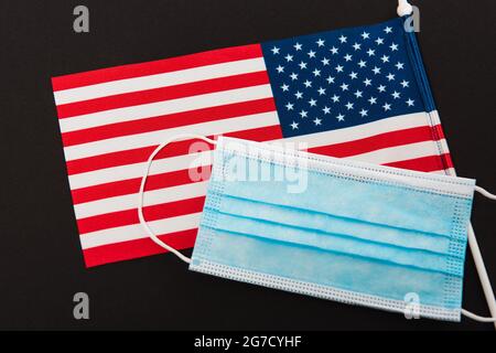 Hochwinkelansicht der blauen medizinischen Maske auf amerikanischer Flagge isoliert auf schwarz Stockfoto