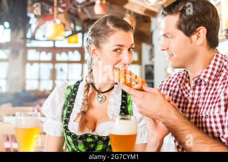 Bayerischen paar tragen traditionelle Kleidung, flirten und trinken Bier im restaurant Stockfoto